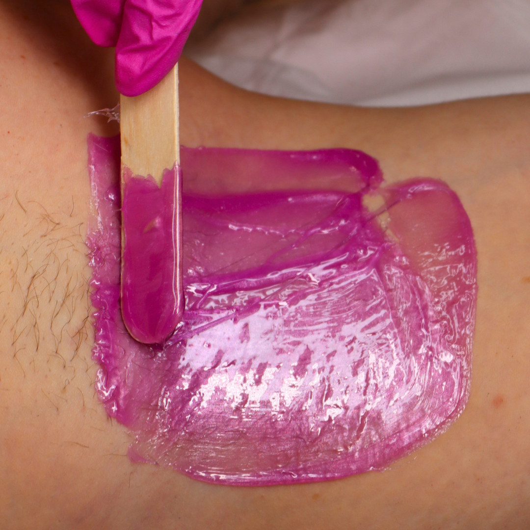 Pinkfishes Siren wax being applied to an armpit with a Pinkfishes Waxing Spatula;