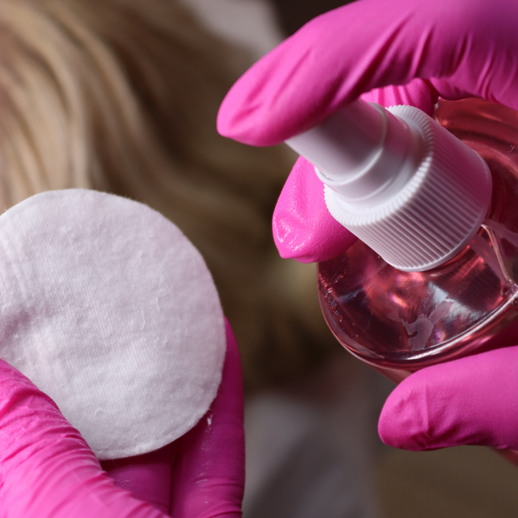 Pre-waxing cleansing spray being sprayed onto a cotton pad.